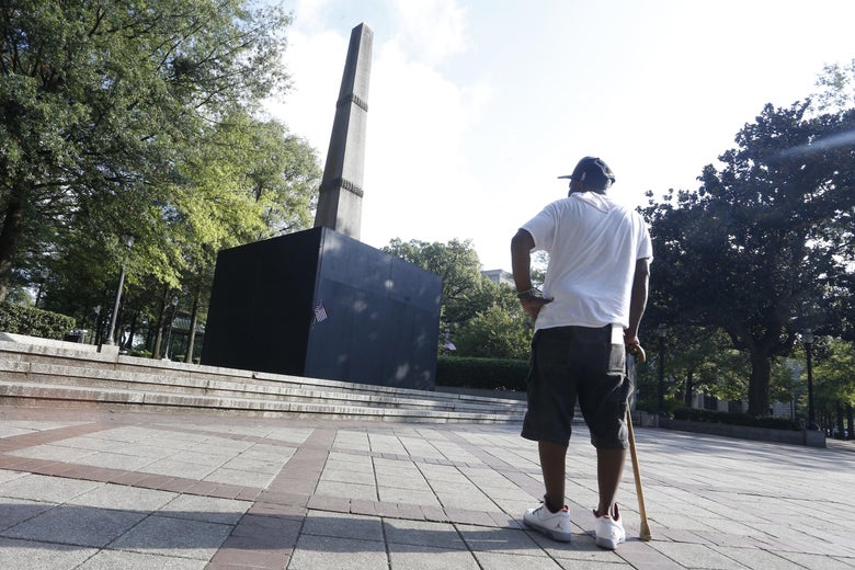 A man with a cane pauses to look at a now covered confederate monument in Linn Park in Birmingham, Alabama.